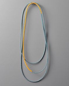 two blue and yellow necklaces on a gray surface with one cord attached to the other