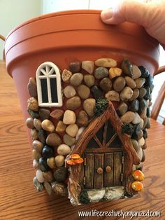 there is a pot with rocks and a house on it