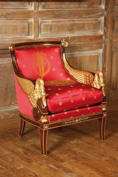 a red and gold chair sitting on top of a hard wood floor next to a wooden wall