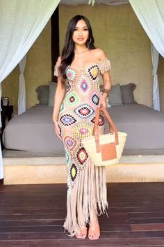 a woman standing in front of a bed wearing a dress with fringes on it