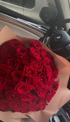 a bouquet of red roses sitting on the dashboard of a car