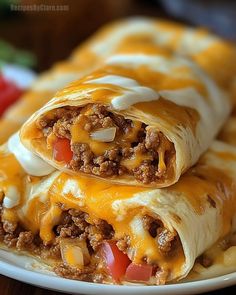 two burritos stacked on top of each other with cheese and meat in them