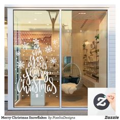 a store front window with christmas decorations on the glass and a hand holding a pen