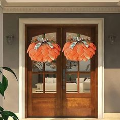 two orange wreaths on the front door of a house