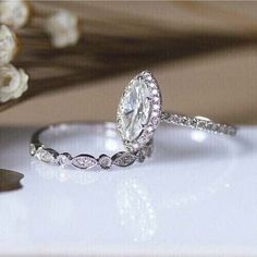 a close up of a ring on a table with flowers in the background and a white rose