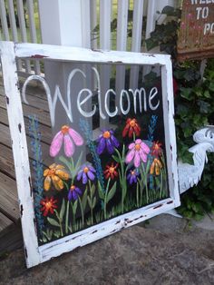 a sign with flowers painted on it that says welcome