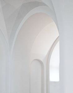 an empty hallway with white walls and arches