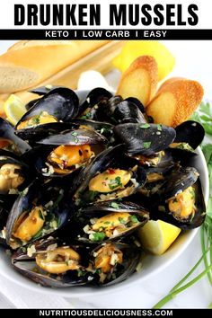 a white bowl filled with mussels next to bread