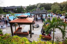 a group of people standing around in front of a pool and pavilion at an outdoor event