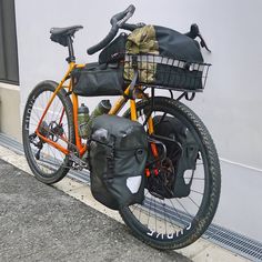 an orange bicycle parked next to a building with a basket on the front and back