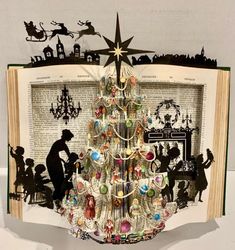 an open book with a christmas tree made out of old books and paper cut outs