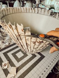 a person cutting fabric with scissors on top of a large piece of paper that has been folded