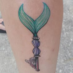 a woman's leg with a tattoo on it that has a green and purple design