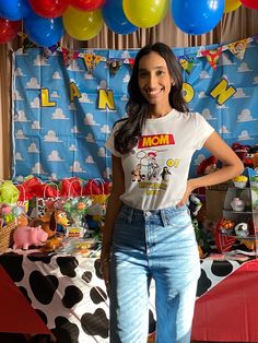 a woman standing in front of a table with balloons and decorations on the wall behind her