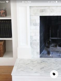 a white fireplace with bookshelves in the background