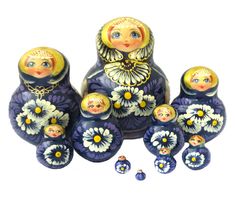 a group of dolls sitting next to each other on top of a white surface with yellow and blue flowers