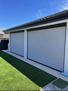 a large white garage door on the side of a house with artificial grass in front of it