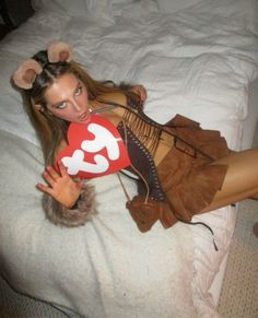 a woman laying on top of a bed with a stuffed animal in her hand and wearing a mouse costume