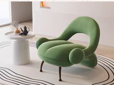 a green chair sitting on top of a white rug next to a table and vase