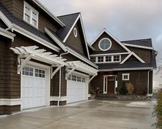 a brown house with white trim and two large garages on the side of it