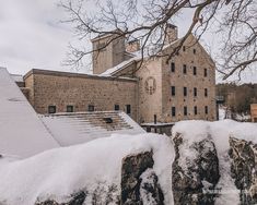 snow covers the rocks and roof of an old building