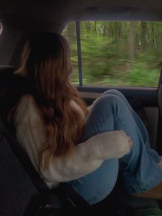 a woman sitting in the back seat of a car with her legs crossed and looking out the window