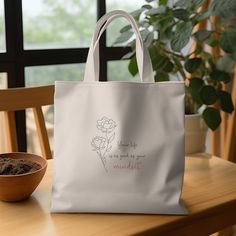 a white bag sitting on top of a wooden table next to a bowl of dirt