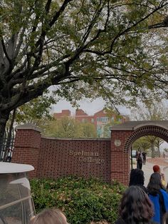 a group of people standing in front of a brick sign