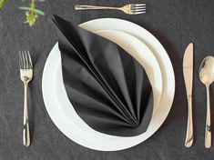 black napkins and silverware are laid out on a white plate