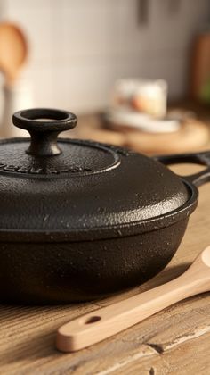 a cast iron skillet sitting on top of a wooden table next to a spatula