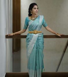 a woman in a blue and white sari is standing on a balcony railing with her arms outstretched