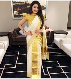 a woman standing in a living room wearing a yellow and white sari