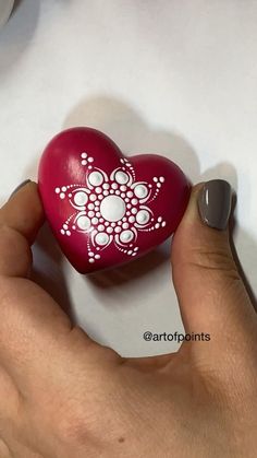 a hand holding a red heart shaped object