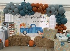 a table with hay bales and balloons in the shape of a truck on it