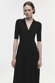 SIGNATURE COLLECTION The Signature Pati Dress in Black. Featuring a flattering V-neck collar and ribbed texture, this midi piece gracefully flows, encapsulating timeless elegance with a modern twist. Ideal for both daywear and evening occasions.