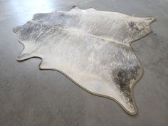 a cowhide rug is laying on the floor in an empty room with concrete floors