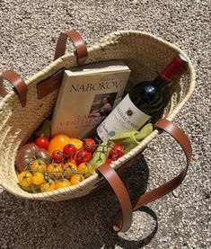 a basket filled with assorted fruits and vegetables next to a bottle of red wine