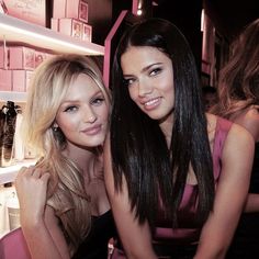 two beautiful young women sitting next to each other in front of shelves filled with cosmetics