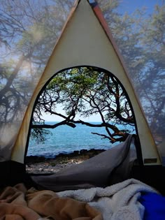 a tent with a view of the ocean through it's window and trees in the foreground