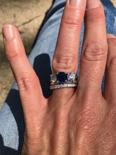 a person's hand with a ring on it and a blue stone in the middle