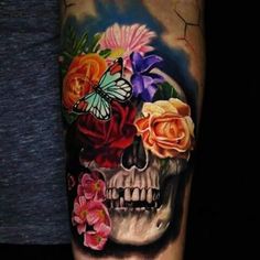 a skull with flowers and a butterfly on it's head is seen in this tattoo design