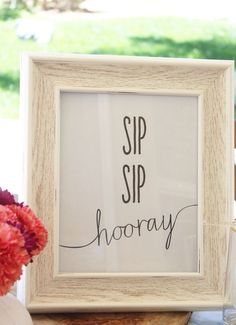 a sign that says sip sip hooray in front of a vase with flowers