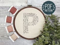 a cross stitch pattern with the letter p surrounded by small spools of thread