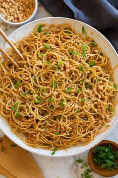 a white bowl filled with noodles and chopsticks on top of a marble counter