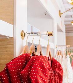 red polka dot dress on hangers in front of white wall and wooden flooring