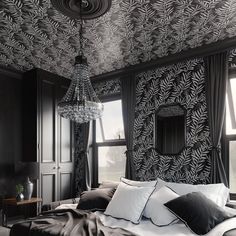 a bedroom with black and white wallpaper, a chandelier and pillows on the bed