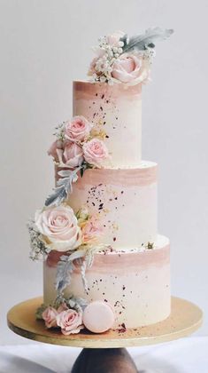 a three tiered wedding cake with pink flowers and greenery on the top layer