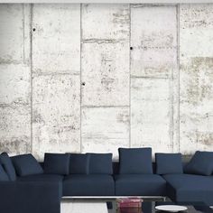 a large blue couch sitting in front of a white wall with concrete blocks on it