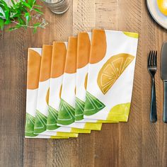 five napkins on top of a wooden table with utensils and lemon slices