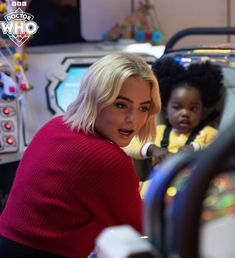 a woman in a red sweater and two children playing video games at the same time